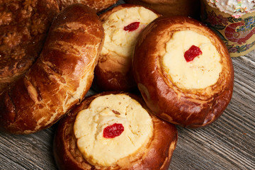 Traditional homemade Russian Easter baked goods, kulichi, patties with cottage cheese, karavai and loaf cake with nuts on festive table background