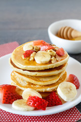 Healthy homemade breakfast with pancakes, strawberry, bananas nuts and honey