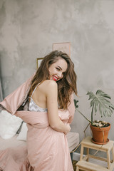 Obraz na płótnie Canvas Shy cute lovely young woman with brown long hair is standing in pink blanket