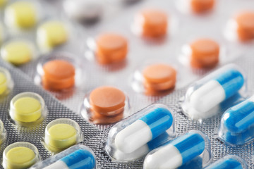 Heap of medical pills in white, blue and other colors. Pills in plastic package. Concept of healthcare and medicine.