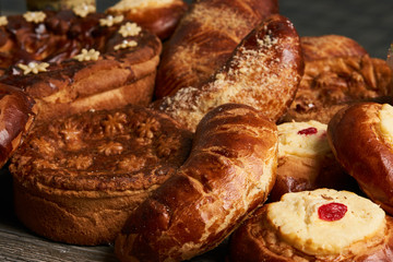 Traditional homemade Russian Easter baked goods, kulichi, patties with cottage cheese, karavai and loaf cake with nuts on festive table background