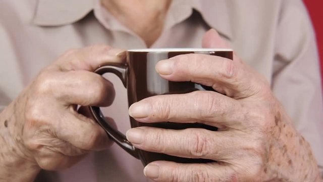 Elderly with a cup of tea. Old hands with a cup of tea.