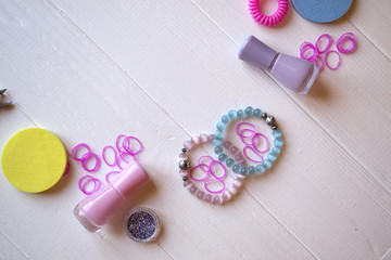 Colorful and bright cosmetics. Beauty care tools. Beauty salon. Girl's paradise.  Nail polishes, sequins, pink hair bands and comb on the white wooden desk. Bright still life of beauty instruments.