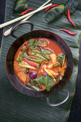 Traditional Thai kaeng phet red curry with vegetables as top view in a wok on a banana leaf