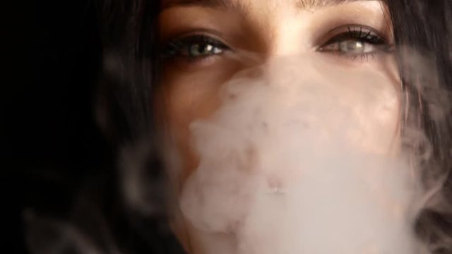 Close up of woman mouth smoking. The girl slowly and sexually releases smoke from an electronic cigarette