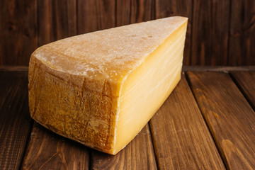Big Piece of Crafted Cheddar Cheese on Wooden Brown Background.
