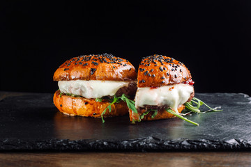 Hamburger on a black slate board. It is cut in half.