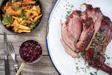 Marinated sliced barbecue aged leg of venison with chanterelles and cherry sauce as top view on rustic background © HLPhoto