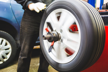 Mechanic aligning car tire at service