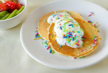 Homemade pancakes for kids with cream and colorful candy sprinkles