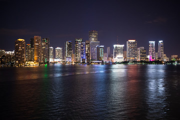 Miami city skyline panorama at night, usa. Skyscrapers illumination reflect on sea water in dusk. Architecture, structure, design. Building, construction, development. Wanderlust, travel, discovery