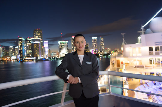 Woman steward on ship board at night in miami, usa. Sensual woman in suit jacket on city skyline. Water transport, transportation. Travelling for business. Wanderlust, adventure, discovery, journey