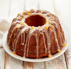 Easter Yeast cake on a white plate  on a wooden table. Traditional Easter cake with raisins and icing with candied orange peel