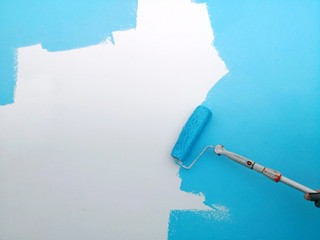 Malerrolle streicht weiße Wand mit heller blauer Farbe, Hintergrund Textfreiraum