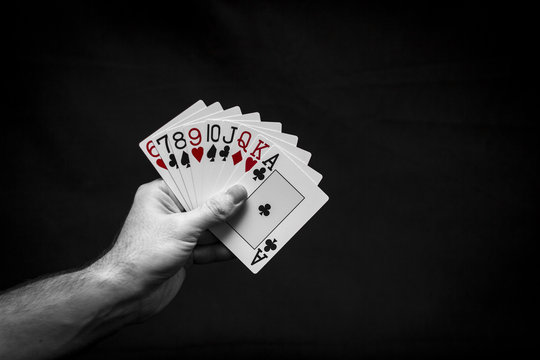Playing cards in hand on a dark background