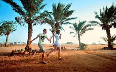 Happy young couple having beach fun on vacation honeymoon travel holidays. Caucasian woman and man playing playful enjoying love on date or honeymoon. Multiracial couple