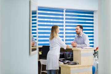 Nurse and patient conversing at reception desk in hospital