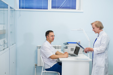 Obraz premium Joyful general practitioners discussing their work at hospital office