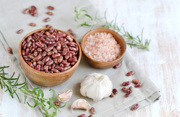 Raw red kidney beans in wooden bowl, rosemary herb, healthy vegetarian food, lunch