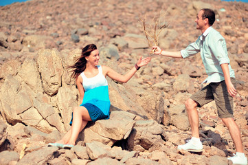 Happy young couple having fun in desert sand on vacation honeymoon travel holidays. Caucasian woman and man playing playful enjoying love on date. Multiracial couple