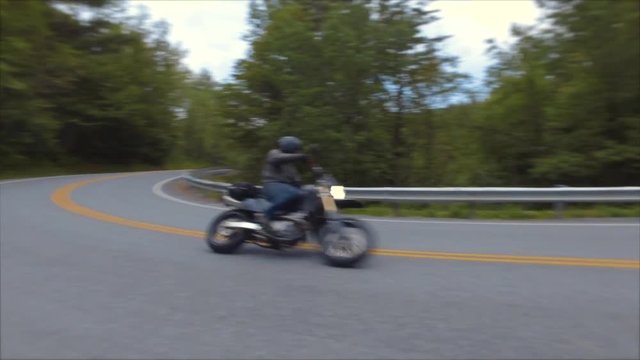 motorcycle rider takes corner fast and leaning hard with leg out for balance gimbal view