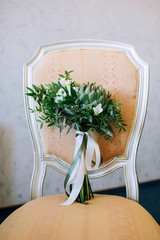 close-up of a wedding bouquet with a green panthey standing on a chair against a gray wall background
