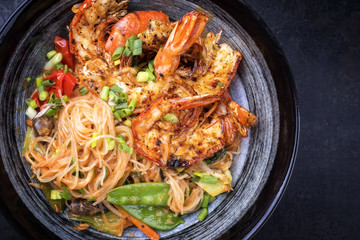 Traditional Thai Phak Kung curry with barbecue king prawns and noodles as top view in a bowl