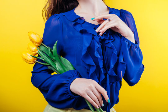 Studio shot of a woman wearing spring outfit and holding yellow tulips