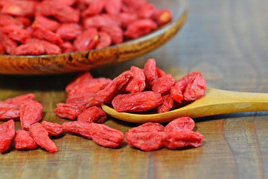 Dried goji berries in wooden spoon and plate (Lycium chinense) macro selective focus
