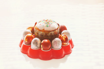 Great Easter cake with colored eggs on a red stand on a light background.