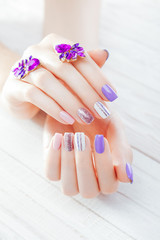 Pastel manicure with earrings on white background. Combination of purple, white, pink colors and...