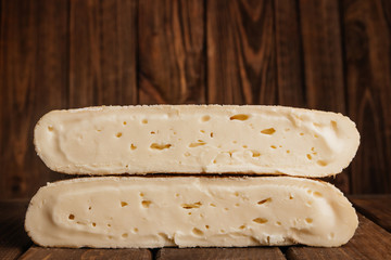 Two Big Pieces of Crafted Cheese on Wooden Brown Background.