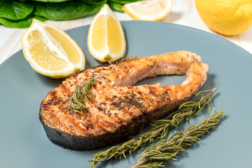 Salmon fillet. Grilled salmon with herb and lemon on plate. Fish roasted on a wooden background.
