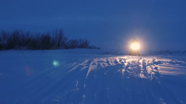 Aerial. A snowmobile is jumping through the snow at night