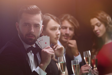 Poker player to four aces over dark background