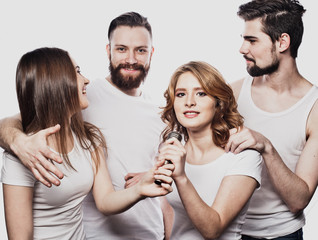 Group of friends playing karaoke over white background. Concept about friendship and people.
