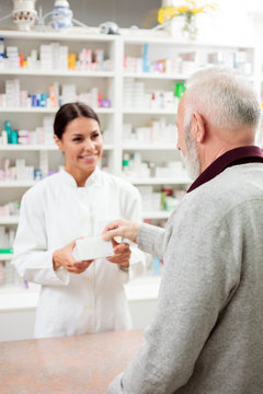 Medicine, pharmaceutics, health care and people concept - Happy female pharmacist giving medications to senior male customer