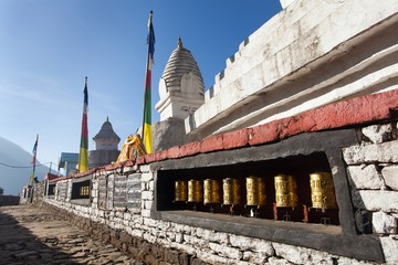 Stupa with prayer flags and wheelsin