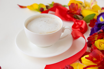krpunny plan white forforo cup with coffee vokruk which lie tulips, narcissus, and orchade with a red bow on a white background