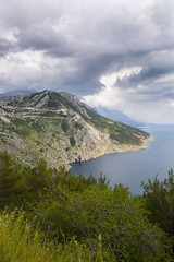 Aerial view on the cliff going down in the adriatic sea with dramatic cloudy sky, Croatia