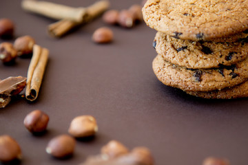 cookies with chocolate around which lie nuts and cinnamon on a dark brown background