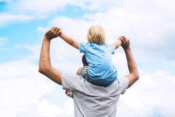 Father and son with raised arms up against the sky.