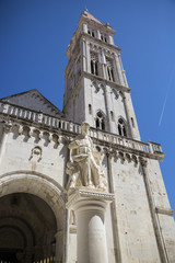 Statue of St Lawrence on St Lawrence square with bell tower of the Cathedral of St. Lawrence and blue sky in the background, Trogir, Croatia,  built in the Romanesque-Gothic style