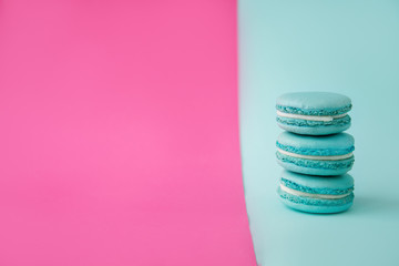 three mint macaroons stand on top of each other on a mint and pink background
