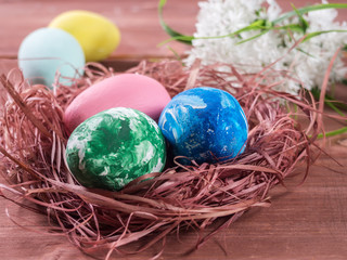 Nest with Easter eggs and spring color on a wooden background