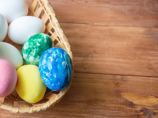 Easter basket with colored eggs and place for an inscription on a wooden