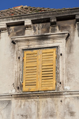 Obraz premium closed yellow wooden shutter of a old house