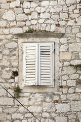 Fototapeta na wymiar closed white wooden shutter of a old stone house