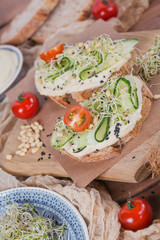 Healthy vegetarian bruschettas with bread, micro greens, hummus, cherry tomatoes, cucumbers and pine nuts