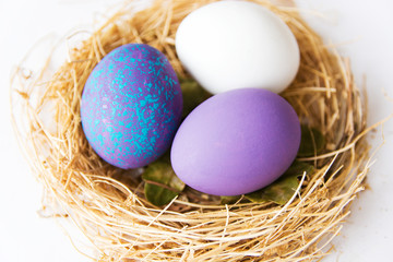 Naklejka na ściany i meble Purple colored Easter eggs in nest on wooden background, selective focus image. Happy Easter card 
